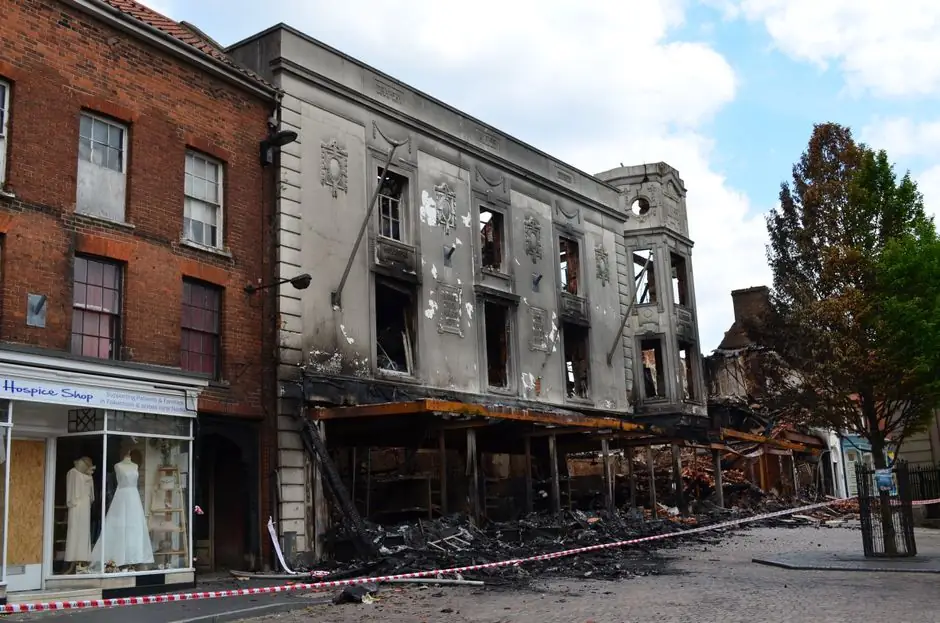 A fire-damaged building stands in an urban street, showcasing destruction and decay.