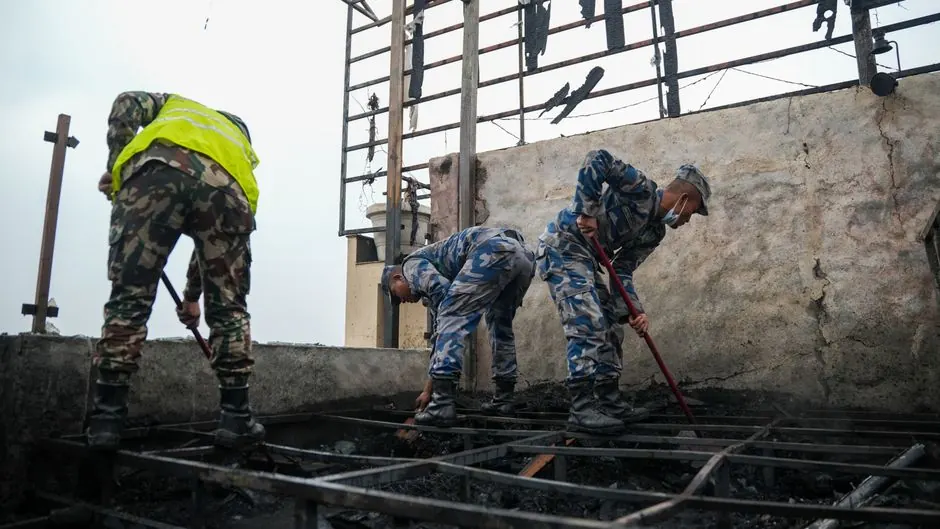 Rescue workers clean up debris on a rooftop in post-fire recovery effort, showcasing determination and teamwork.